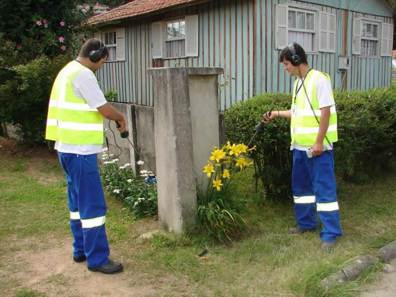   Com a proximidade do verão, o consumo de água começa aumentar. Então, visando reduzir o desperdício de água e evitar problemas na estação mais quente do ano, a Tubarão Saneamento, empresa responsável pelo sistema de água e esgoto da Cidade Azul, está realizando um trabalho técnico, com o intuito de localizar vazamentos não visíveis. A ação vem trazendo resultados positivos à Concessionária.<br>  Para o desenvolvimento do projeto, todas às noites e início das manhãs, uma equipe vai às ruas com um aparelho chamado geofone eletrônico, utilizado para detectar vazamentos não visíveis, por meio de escuta no solo. Além desse equipamento, os colaboradores usam nesta atividade, haste de escuta e de perfuração, além de uma válvula geradora de ondas.<br>  O supervisor de serviços operacionais, Mayckel Seiffert Pereira, explica que o geofone é um aparelho extremamente sensível a ruídos. “Esses serviços normalmente são realizados durante a madrugada, já que neste período a intensidade de barulho do ambiente é menor, o que facilita ao encontrar um problema”, afirma.<br>  Pelo fone de ouvido, o operador do geofone consegue qualificar um ruído como sendo de vazamento e pelo indicador de intensidade localiza o ponto exato do problema. “Ao detectar que o líquido está escapando, o geofone transmite ao fone de ouvido do funcionário um som característico, tornando possível a identificação e localização do vazamento não visível”, disse o supervisor.<br>  De acordo com o diretor técnico da Tubarão Saneamento, Rondinaldo Paiva de Lima, a pesquisa tem o objetivo de reduzir perdas físicas de água. “Além de combater a perda de água tratada, estamos diminuindo a possibilidade de existir falta de abastecimento em algumas residências”, disse o profissional, ressaltando que assim que o vazamento é identificado, durante a madrugada, o conserto é programado para o dia seguinte.<br>  A meta da empresa concessionária é realizar uma varredura de 40 a 50 km, por mês, nas ruas de Tubarão.